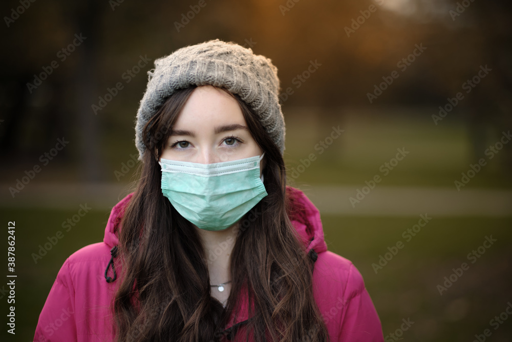 Women wearing face mask, jacket and hat on cold winter day in the park Women wearing face mask, jacket and hat on cold winter day in the park