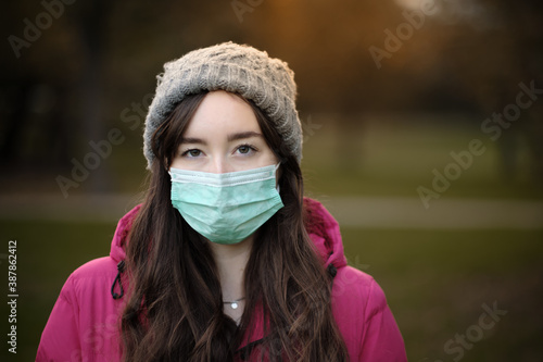 Women wearing face mask, jacket and hat on cold winter day in the park © Leonard