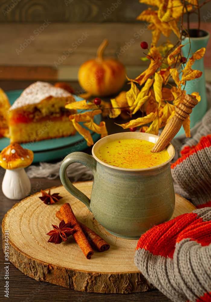 Golden turmeric milk with cinnamon, honey, and ginger in an autumn decor Golden turmeric milk with cinnamon, honey, and ginger in an autumn decor