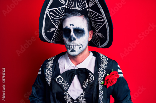 Young man wearing mexican day of the dead costume over red with hand on stomach because indigestion, painful illness feeling unwell. ache concept.