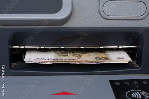 Russian rubles sticking out of an ATM close-up. Cash withdrawal of money from a bank account