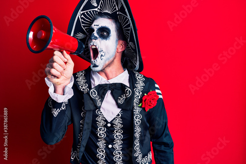 Scary man wearing day of the dead make up and costumbre from traditional ritual in Mexico shouting through megaphone