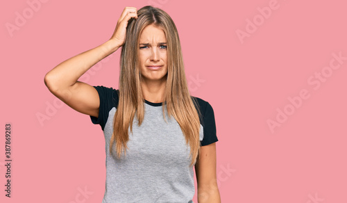Young blonde woman wearing casual clothes confuse and wonder about question. uncertain with doubt, thinking with hand on head. pensive concept.