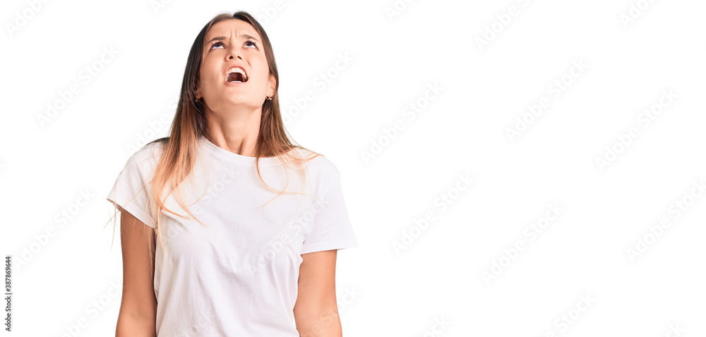 Beautiful caucasian woman wearing casual white tshirt angry and mad screaming frustrated and furious, shouting with anger. rage and aggressive concept. Beautiful caucasian woman wearing casual white tshirt angry and mad screaming frustrated and furious, shouting with anger. rage and aggressive concept.
