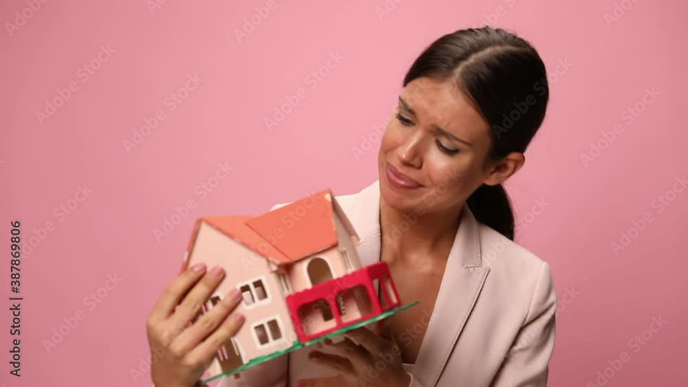young woman in pink suit holding and presenting building model, smiling and making thumbs up gesture on pink background young woman in pink suit holding and presenting building model, smiling and making thumbs up gesture on pink background