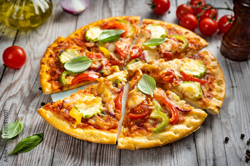 Slices of vegetarian pizza on wooden tray and rustic background