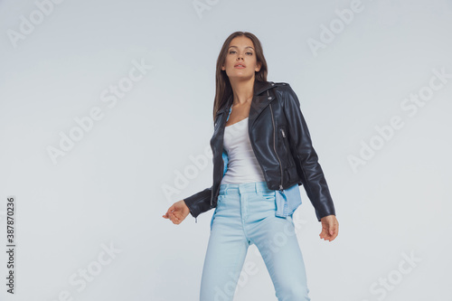 Charming fashion model wearing leather jacket while standing