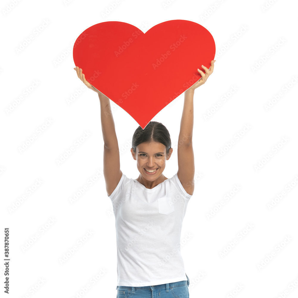 Cheerful casual woman holding heart shape above her head