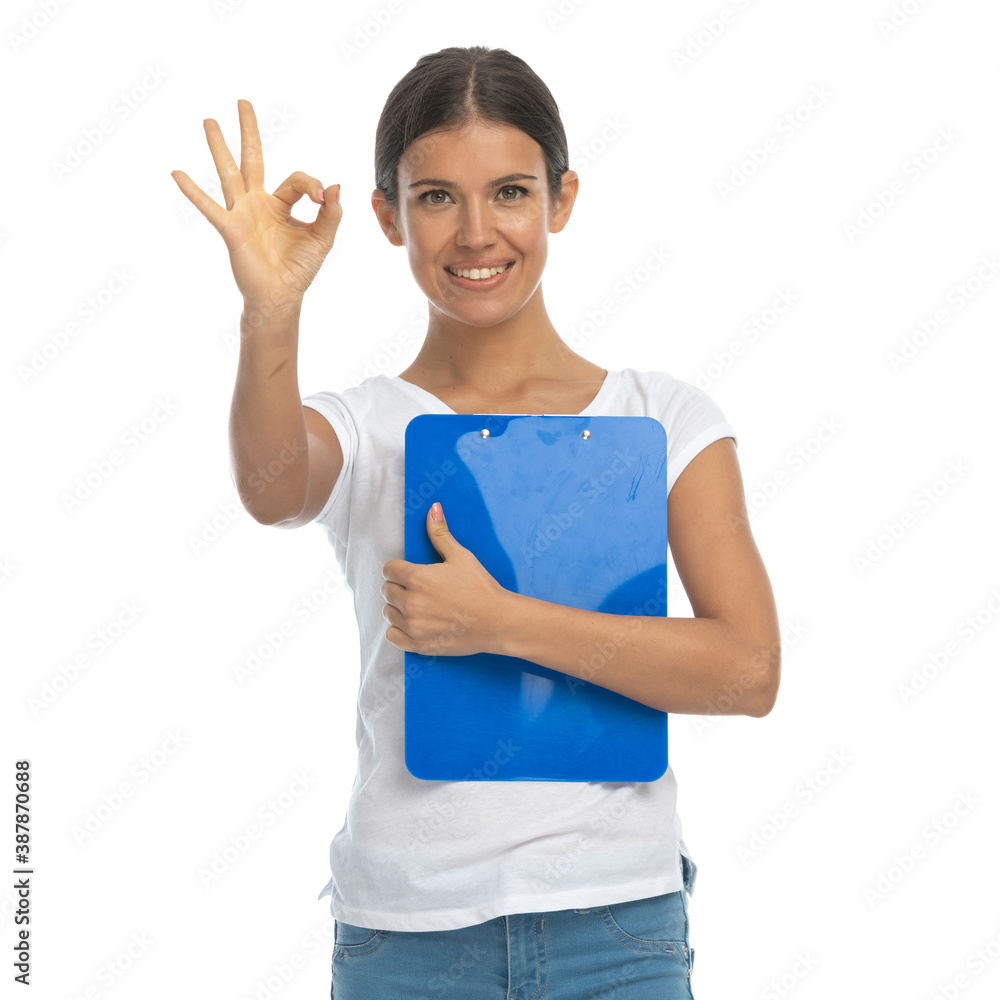 Positive casual woman holding clipboard and gesturing perfect Positive casual woman holding clipboard and gesturing perfect