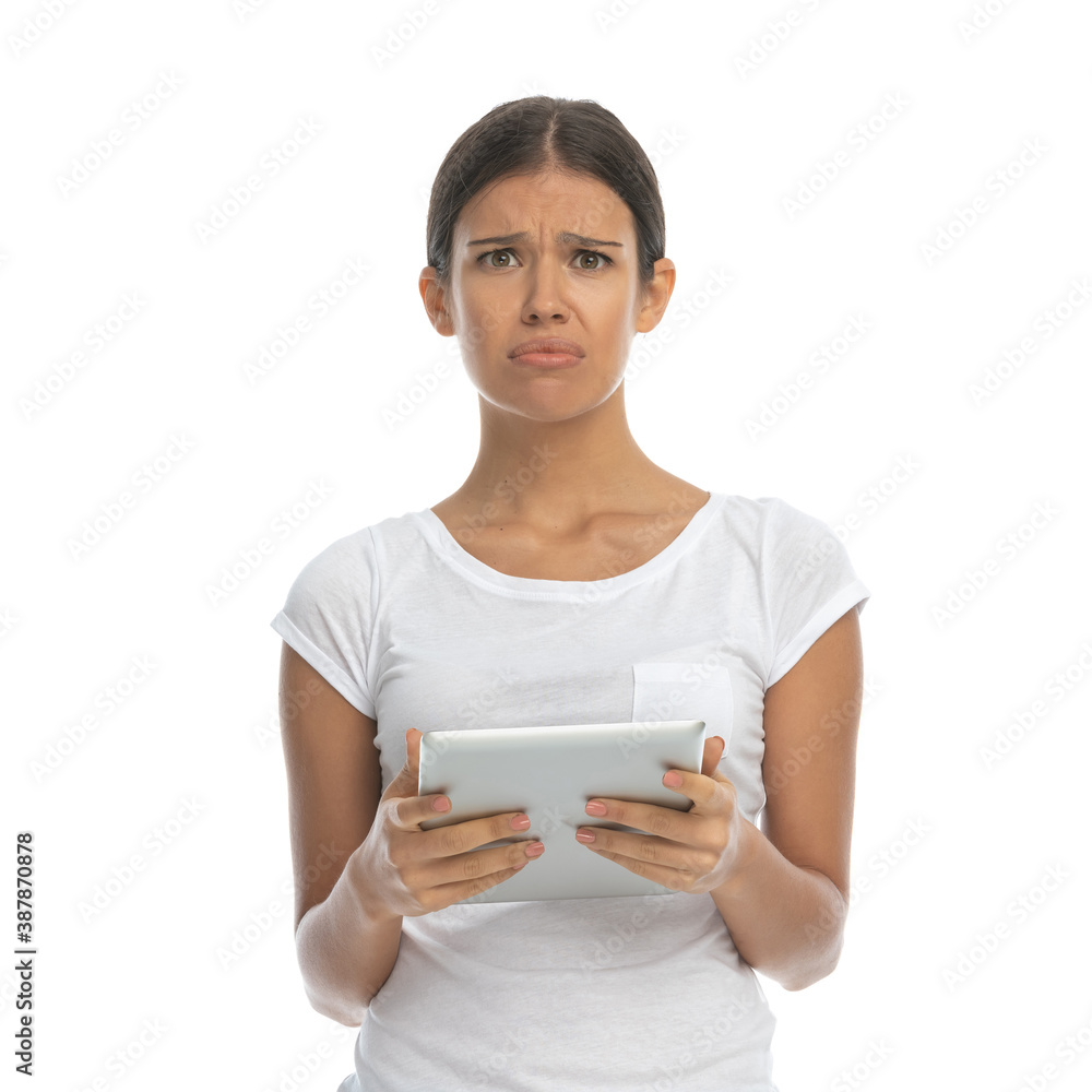 Upset casual woman holding tablet while standing Upset casual woman holding tablet while standing