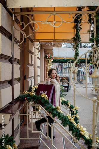 Happy girl holds paperbags with symbol of sale in the stores with sales at Christmas, around the city. Concept of shopping, holidays, happiness, Christmas Sales. © volody10