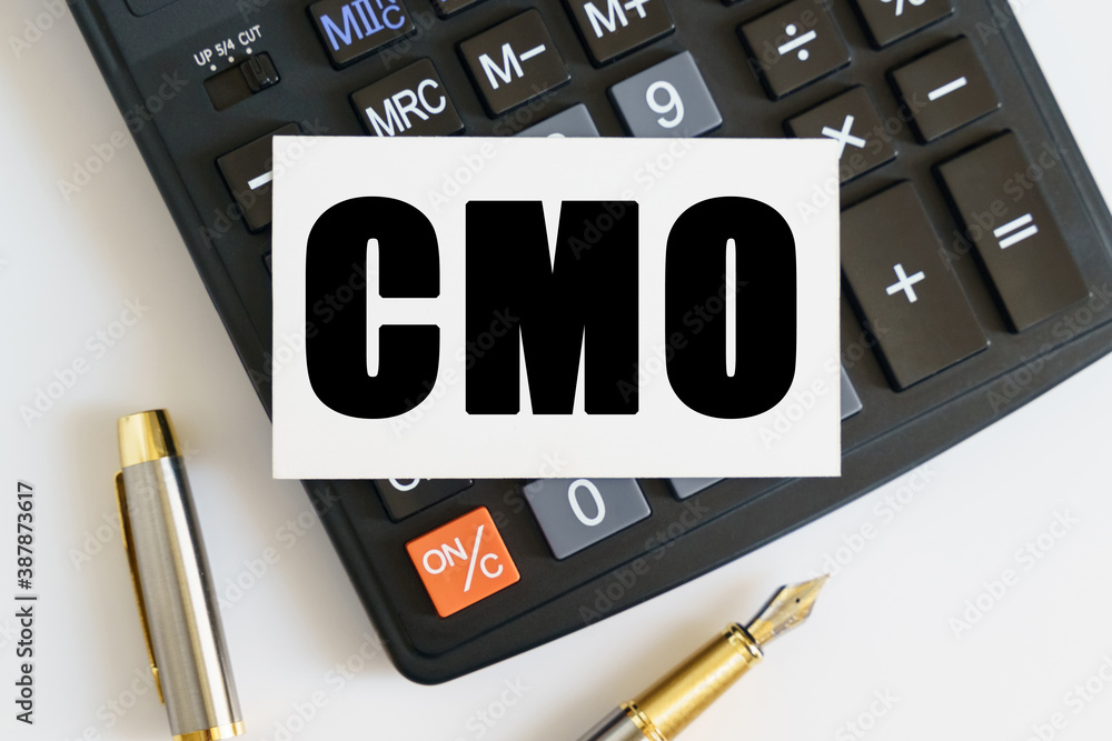 On the table there is a pen, a calculator and a business card on which the text is written CMO. CHIEF MARKETING OFFICER On the table there is a pen, a calculator and a business card on which the text is written CMO. CHIEF MARKETING OFFICER