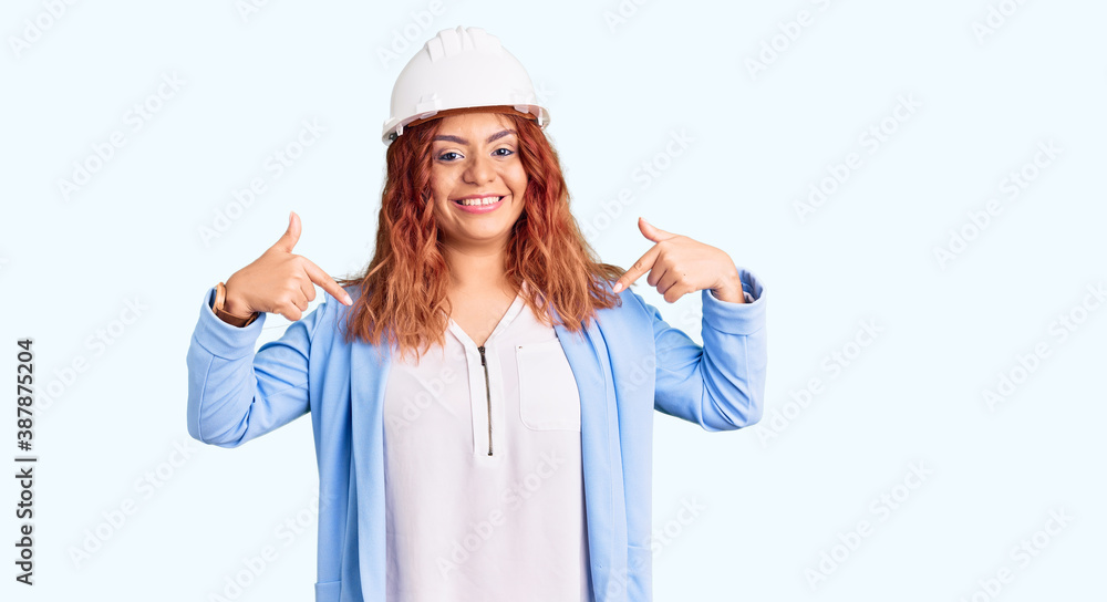 Young latin woman wearing architect hardhat looking confident with smile on face, pointing oneself with fingers proud and happy. Young latin woman wearing architect hardhat looking confident with smile on face, pointing oneself with fingers proud and happy.
