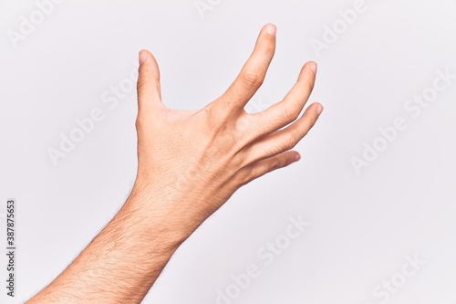 Close up of hand of young caucasian man over isolated background grasping aggressive and scary with fingers, violence and frustration