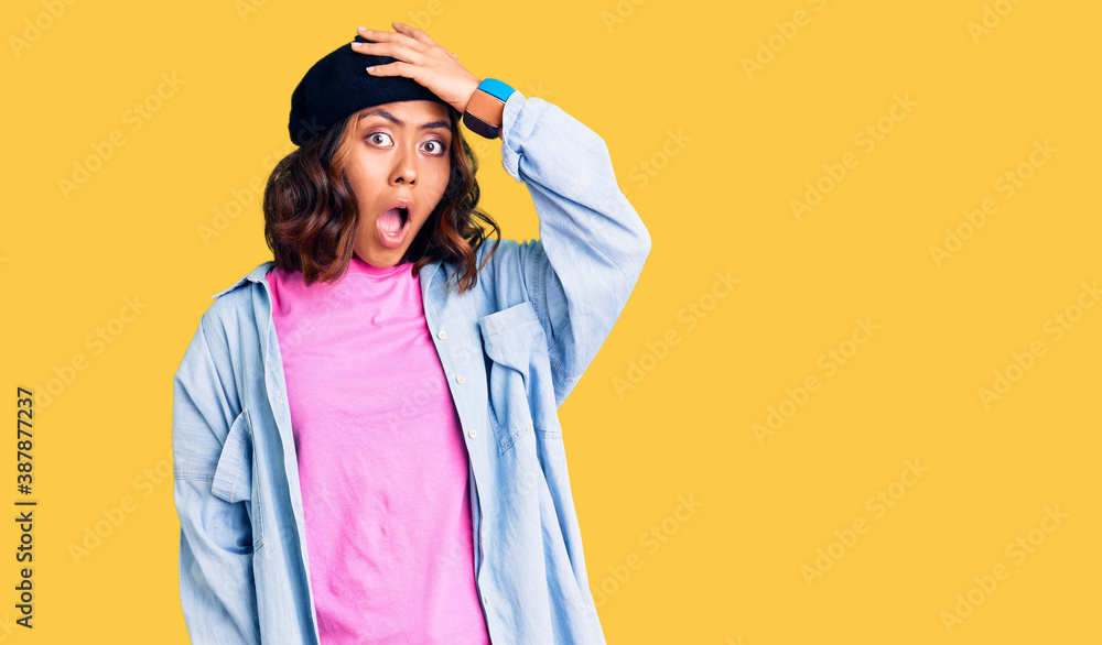 Young beautiful mixed race woman wearing french look with beret surprised with hand on head for mistake, remember error. forgot, bad memory concept. Young beautiful mixed race woman wearing french look with beret surprised with hand on head for mistake, remember error. forgot, bad memory concept.