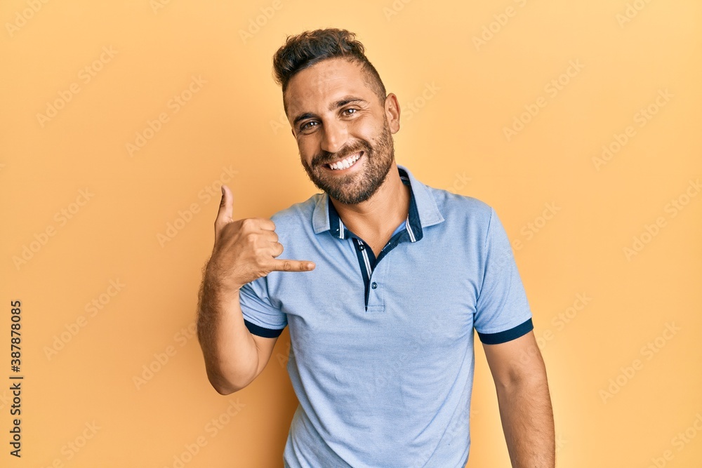 Handsome man with beard wearing casual clothes smiling doing phone gesture with hand and fingers like talking on the telephone. communicating concepts. Handsome man with beard wearing casual clothes smiling doing phone gesture with hand and fingers like talking on the telephone. communicating concepts.