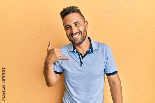 Handsome man with beard wearing casual clothes smiling doing phone gesture with hand and fingers like talking on the telephone. communicating concepts.