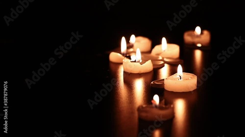Group of candles burning in a dark environment.