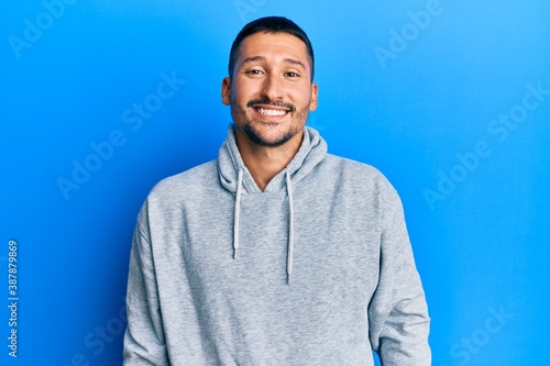 Handsome man with tattoos wearing casual sweatshirt with a happy and cool smile on face. lucky person. © Krakenimages.com