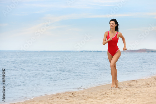 Beautiful female lifeguard running at sandy beach