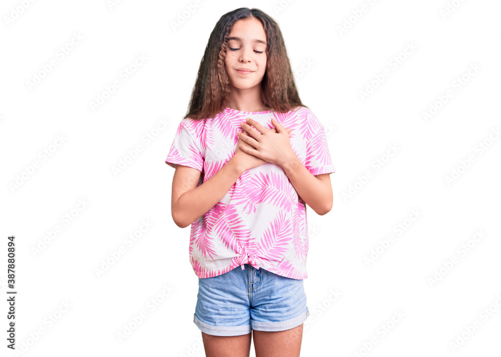 Cute hispanic child girl wearing casual clothes smiling with hands on chest with closed eyes and grateful gesture on face. health concept. Cute hispanic child girl wearing casual clothes smiling with hands on chest with closed eyes and grateful gesture on face. health concept.