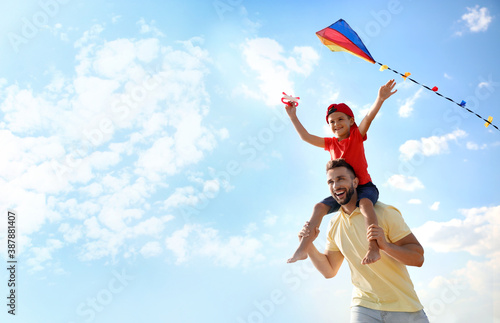 Happy father and his child playing with kite on sunny day. Spending time in nature photo