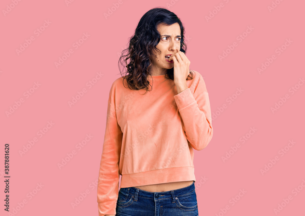 Young beautiful hispanic woman wearing casual clothes looking stressed and nervous with hands on mouth biting nails. anxiety problem. Young beautiful hispanic woman wearing casual clothes looking stressed and nervous with hands on mouth biting nails. anxiety problem.