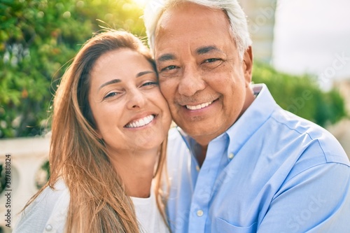 Middle age hispanic couple smiling happy hugging at the promenade. © Krakenimages.com