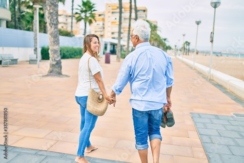 Middle age hispanic couple smiling happy walking at the promenade