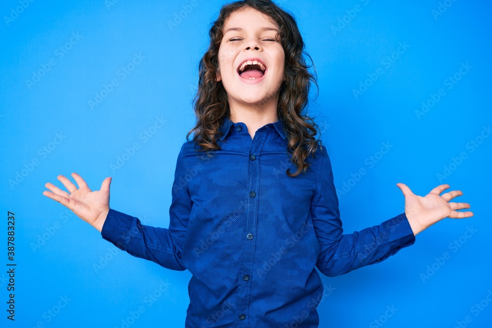 Cute hispanic child with long hair wearing casual clothes celebrating mad and crazy for success with arms raised and closed eyes screaming excited. winner concept Cute hispanic child with long hair wearing casual clothes celebrating mad and crazy for success with arms raised and closed eyes screaming excited. winner concept