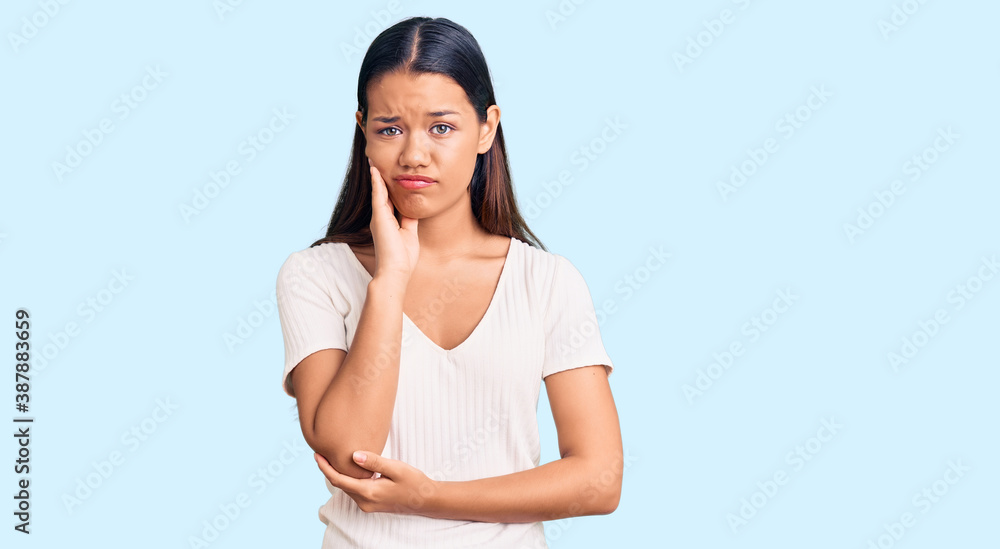 Young beautiful latin girl wearing casual white t shirt thinking looking tired and bored with depression problems with crossed arms. Young beautiful latin girl wearing casual white t shirt thinking looking tired and bored with depression problems with crossed arms.
