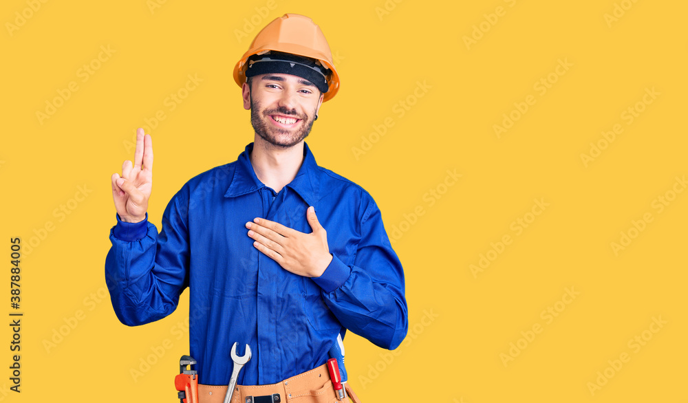 Young hispanic man wearing worker uniform smiling swearing with hand on chest and fingers up, making a loyalty promise oath Young hispanic man wearing worker uniform smiling swearing with hand on chest and fingers up, making a loyalty promise oath