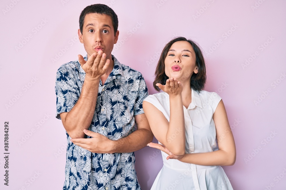 Beautiful couple wearing casual clothes looking at the camera blowing a kiss with hand on air being lovely and sexy. love expression. Beautiful couple wearing casual clothes looking at the camera blowing a kiss with hand on air being lovely and sexy. love expression.