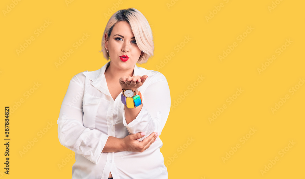 Young blonde plus size woman wearing casual shirt looking at the camera blowing a kiss with hand on air being lovely and sexy. love expression. Young blonde plus size woman wearing casual shirt looking at the camera blowing a kiss with hand on air being lovely and sexy. love expression.