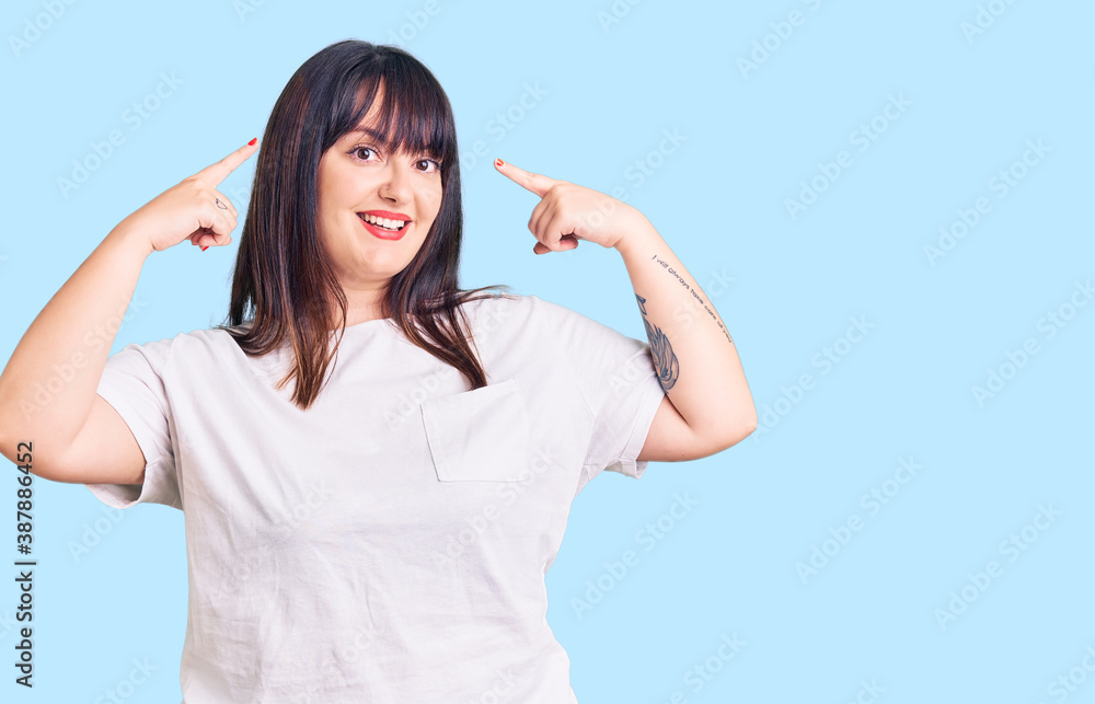 Fototapeta premium Young plus size woman wearing casual clothes smiling pointing to head with both hands finger, great idea or thought, good memory