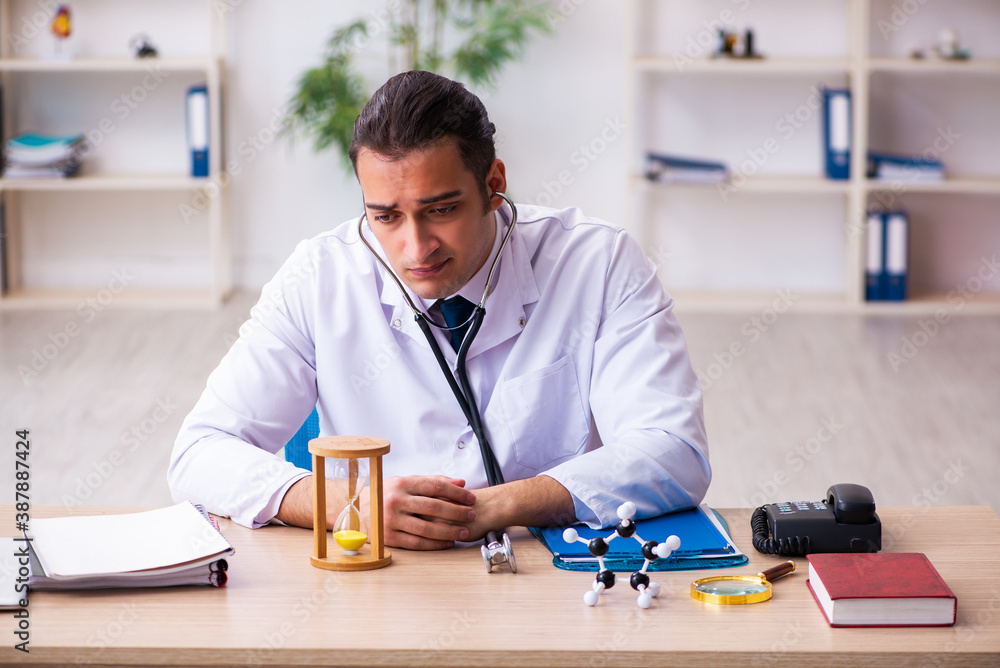 Young male doctor in time management concept Young male doctor in time management concept