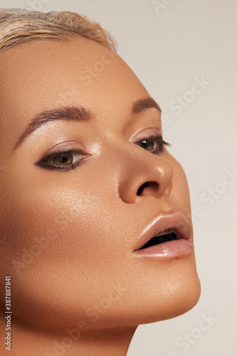 Close-up beautiful young woman with smooth tanned skin. Beauty model with natural bronze make-up, fashion eyeshadows