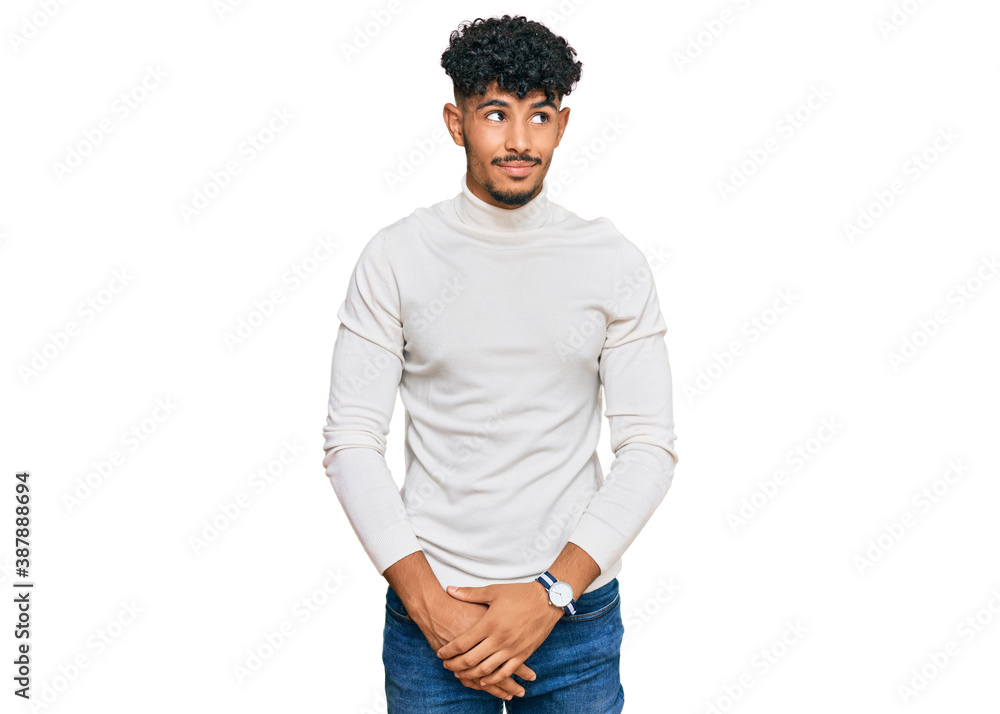 Young arab man wearing casual winter sweater smiling looking to the side and staring away thinking. Young arab man wearing casual winter sweater smiling looking to the side and staring away thinking.