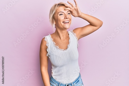 Young blonde girl wearing casual clothes very happy and smiling looking far away with hand over head. searching concept. © Krakenimages.com