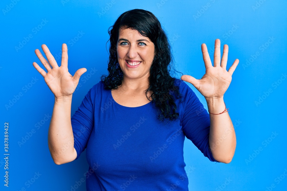 Plus size brunette woman wearing casual blue shirt showing and pointing up with fingers number ten while smiling confident and happy. Plus size brunette woman wearing casual blue shirt showing and pointing up with fingers number ten while smiling confident and happy.