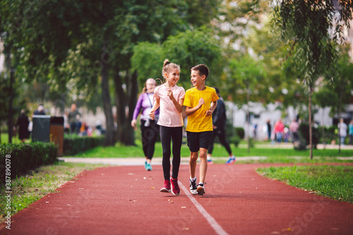 Kids run. Healthy sport. Child sport, heterosexual twins running on track, fitness. Joint training. Running training outdoor brother and sister pre-teen. Jogging with friend. Children athletes