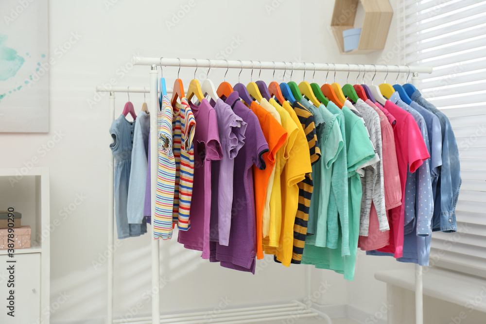Different child's clothes hanging on racks indoors
