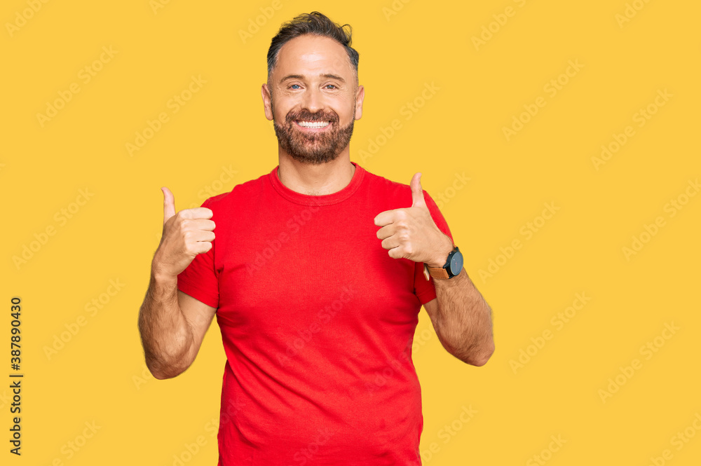 Handsome middle age man wearing casual red tshirt success sign doing positive gesture with hand, thumbs up smiling and happy. cheerful expression and winner gesture. Handsome middle age man wearing casual red tshirt success sign doing positive gesture with hand, thumbs up smiling and happy. cheerful expression and winner gesture.