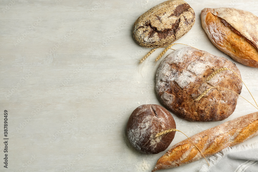 Different kinds of fresh bread on white wooden table, flat lay. Space for text Different kinds of fresh bread on white wooden table, flat lay. Space for text