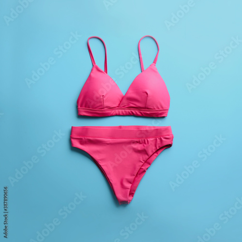 Beautiful pink bikini on light blue background, top view