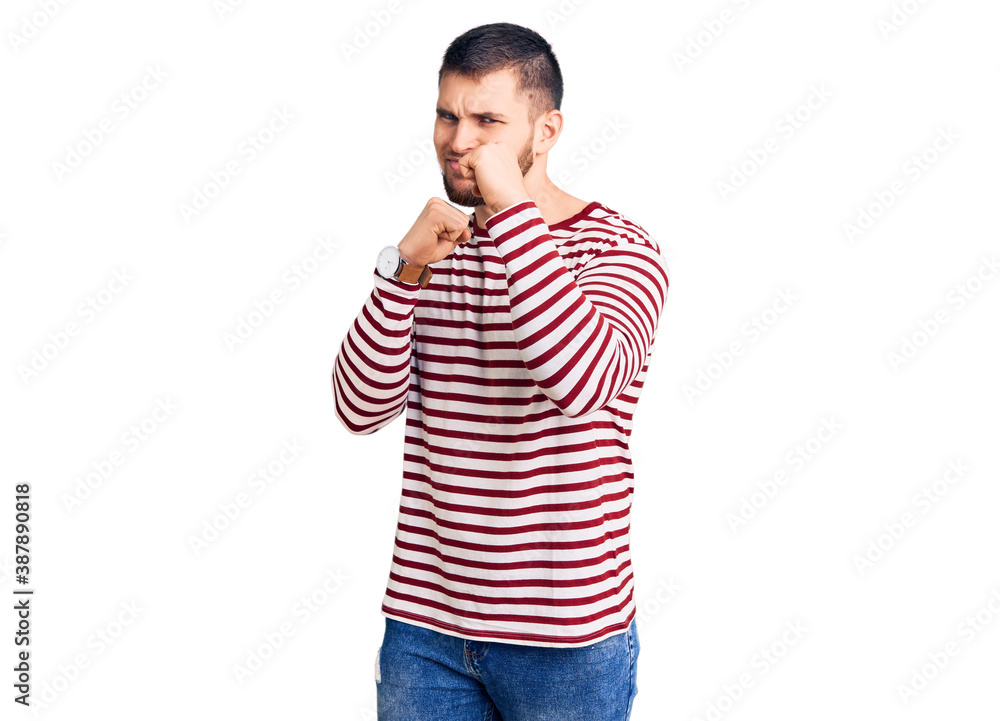 Young handsome man wearing striped sweater ready to fight with fist defense gesture, angry and upset face, afraid of problem Young handsome man wearing striped sweater ready to fight with fist defense gesture, angry and upset face, afraid of problem