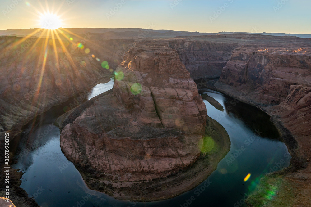 Sun flare on horizon over over canyon with river 