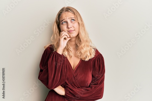 Young blonde girl wearing casual clothes serious face thinking about question with hand on chin, thoughtful about confusing idea