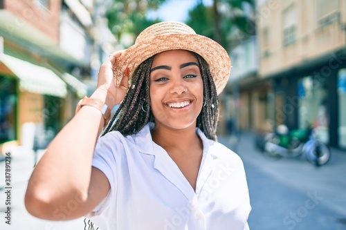 Young african american woman with braids smiling happy outdoors on a sunny day of summer © Krakenimages.com