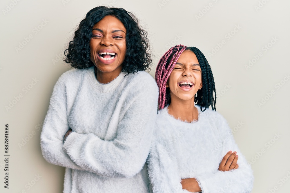 Beautiful african american mother and daughter with arms crossed gesture smiling and laughing hard out loud because funny crazy joke. Beautiful african american mother and daughter with arms crossed gesture smiling and laughing hard out loud because funny crazy joke.